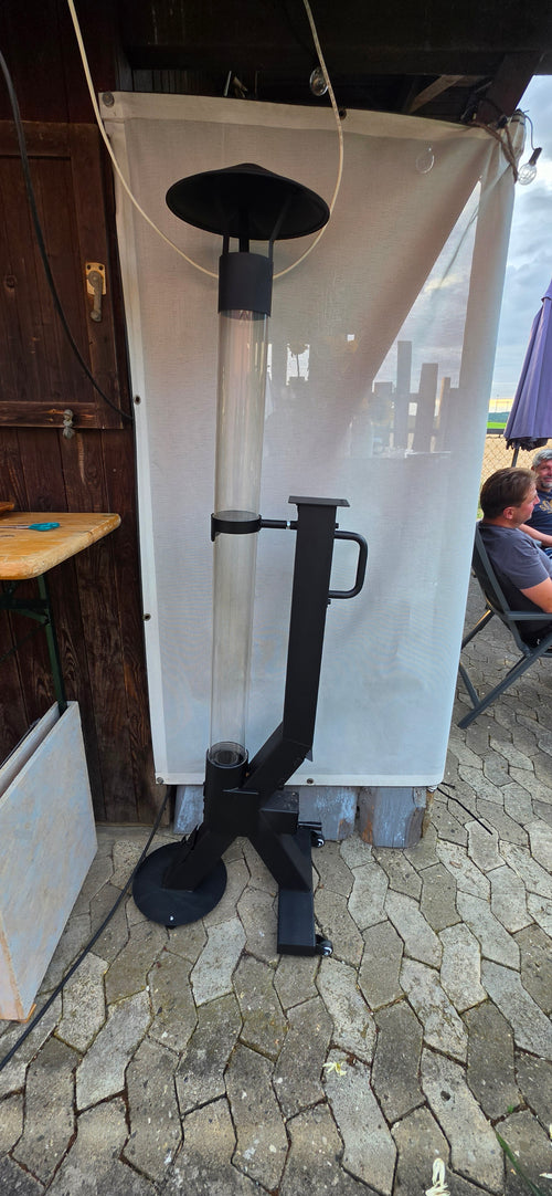 Flamesa buitenhaard op pellets naast een opgevouwen parasol op een terras met natuurstenen tegels