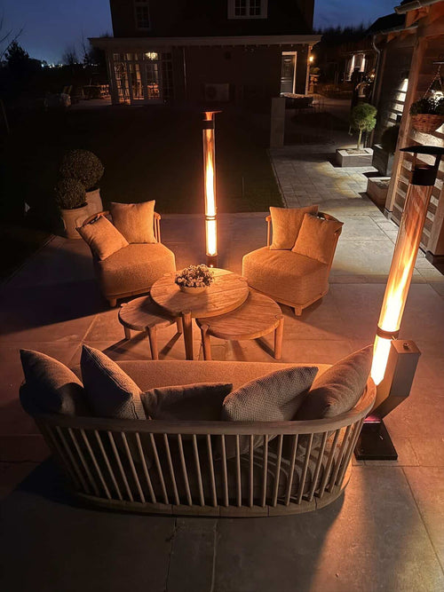 Twee pellethaarden rond een groot rond loungebed met kussens op een avondterras