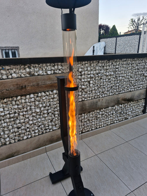 Buitenhaard op pellets brandt naast een schanskorfmuur op een licht getegeld terras