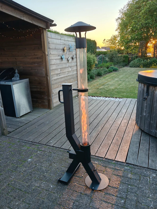 Tuinhaard op pellets brandt bij zonsondergang op een vlonder naast een houten hottub