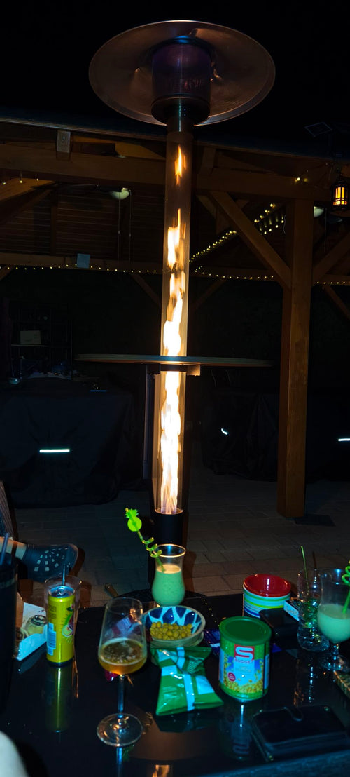 Flamesa terraskachel op pellets verlicht een feestelijk gedekte bartafel met cocktails in het donker