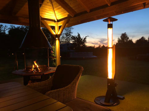 Flamesa pellethaard geeft warm avondlicht naast een rieten loungeset en een vuurtafel
