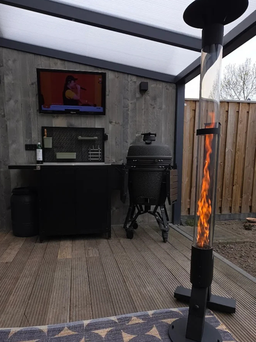 Flamesa sfeerhaard voor buiten onder een overkapping bij een buitenkeuken met kamado barbecue en tv