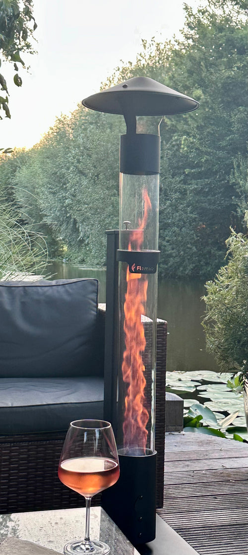 Detail van de brandende glasbuis van een terrasverwarmer op pellets met een glas rosé op de voorgrond