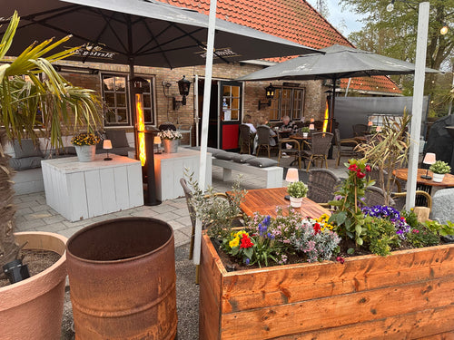 Twee terrasverwarmers op pellets op een horecaterras met parasols, plantenbakken en loungebanken