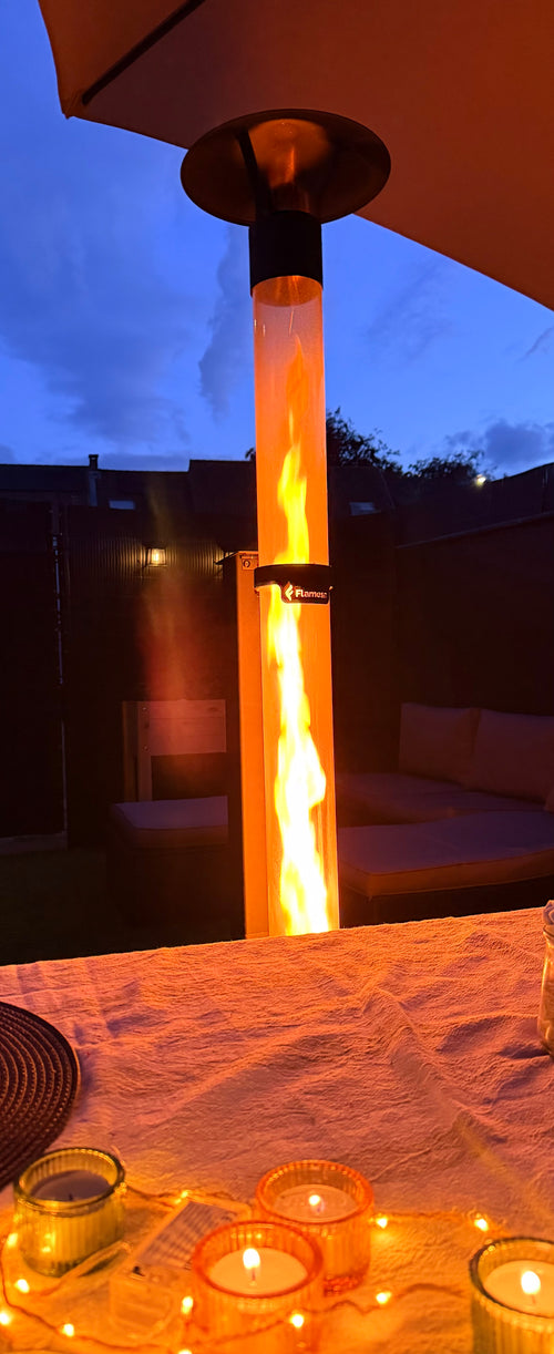 Flamesa pelletkachel onder een parasol bij avondblauw met waxinelichtjes op een gedekte tafel