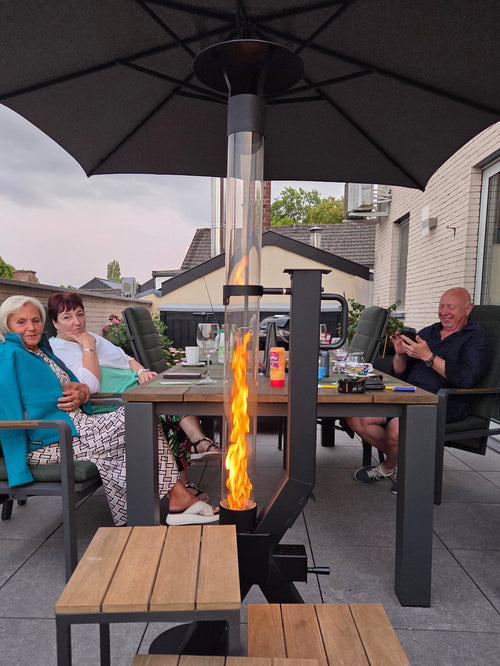 Flamesa pelletkachel voor buiten staat brandend onder een parasol bij een gezelschap aan de tuintafel