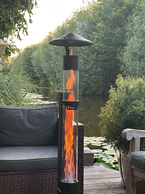 Flamesa pelletkachel voor buiten op een vlonder aan het water met loungestoel en waterlelies