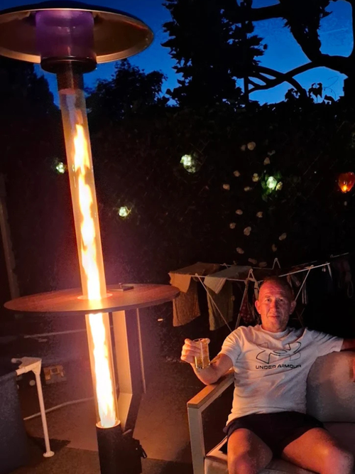 Man met een glas in de hand ontspant 's avonds naast een brandende pellethaard