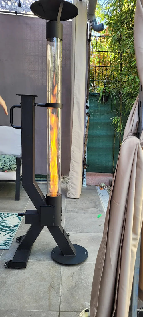 Flamesa vuurzuil op pellets brandt naast een parasol en loungeset op een terras met beschermhoes
