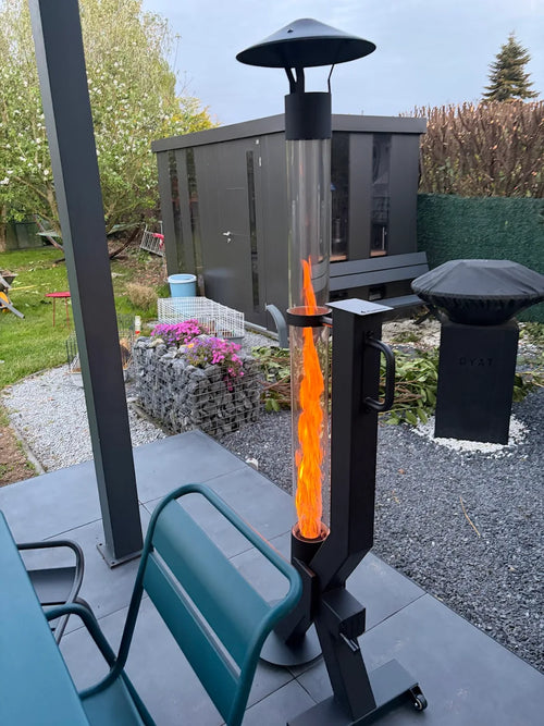 Pelletkachel voor buiten naast turquoise tuinstoelen met een tuinberging op de achtergrond