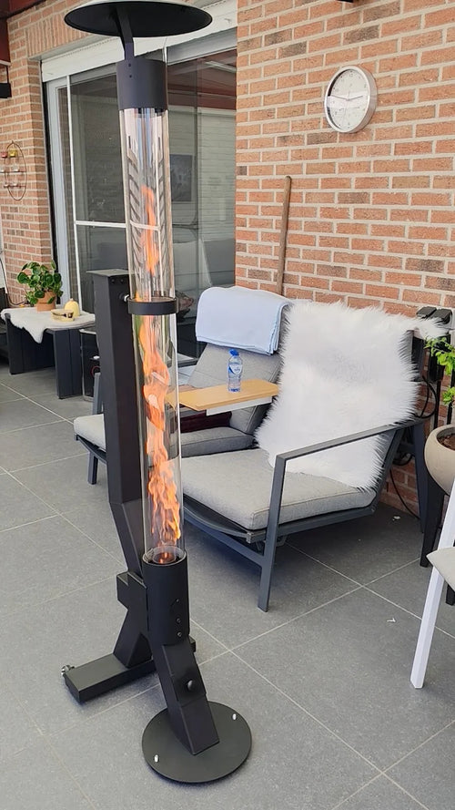 Pellethaard brandt op een terras met loungeset en gedekte tafel langs een bakstenen gevel