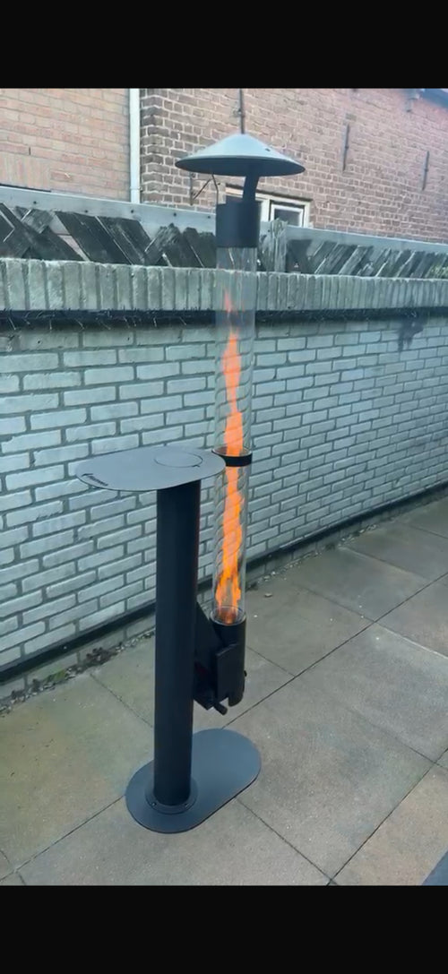 Flamesa sfeerhaard voor buiten brandt op een terras voor een lichte bakstenen muur