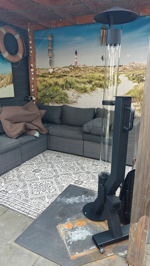 Pelletkachel voor buiten in een tuinkamer met strandmuurschildering en grijze hoekbank