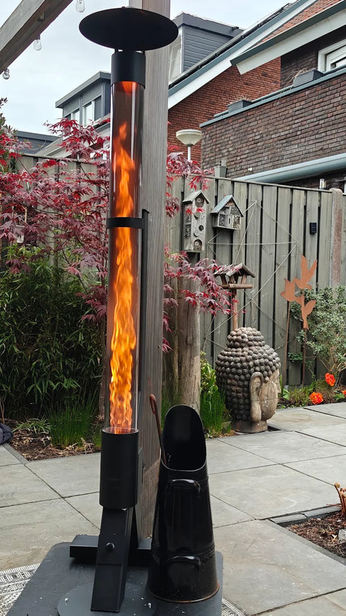 Twee tuinhaarden op pellets op een terras bij een schutting met vogelhuisjes en rode esdoorn