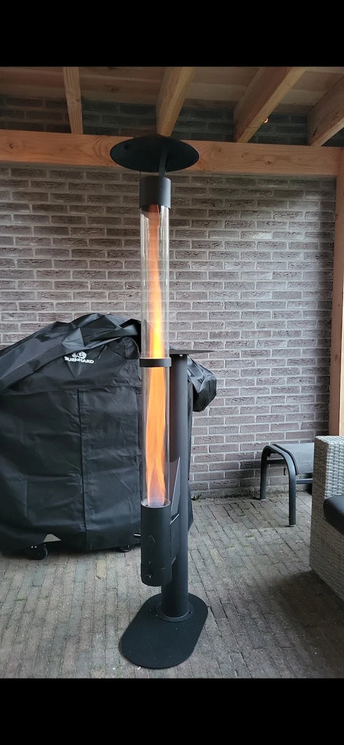 Buitenhaard op pellets brandt onder een overkapping naast de opbergtas voor de kachel