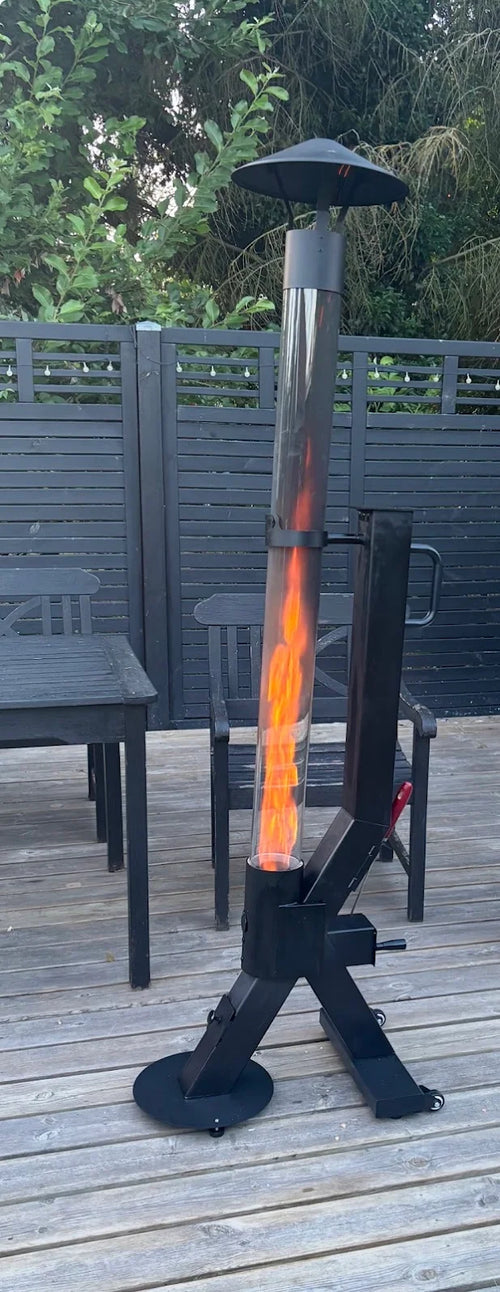 Flamesa pelletkachel op een houten vlonder naast een tuintafel bij een grijze schutting