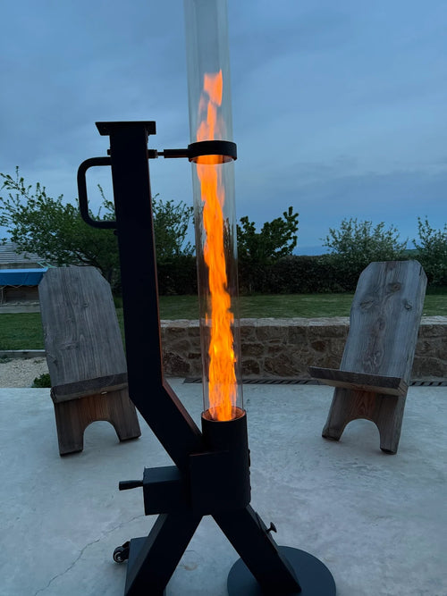 Pelletkachel voor buiten met felle vlam tussen twee houten tuinstoelen op een betonnen terras