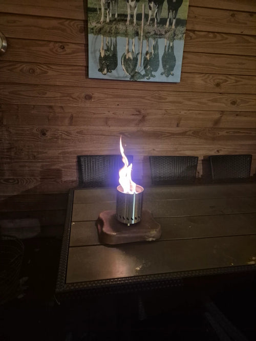 Kleine Flamesa tafelhaard met blauwe vlam op een tuintafel in een tuinhuis