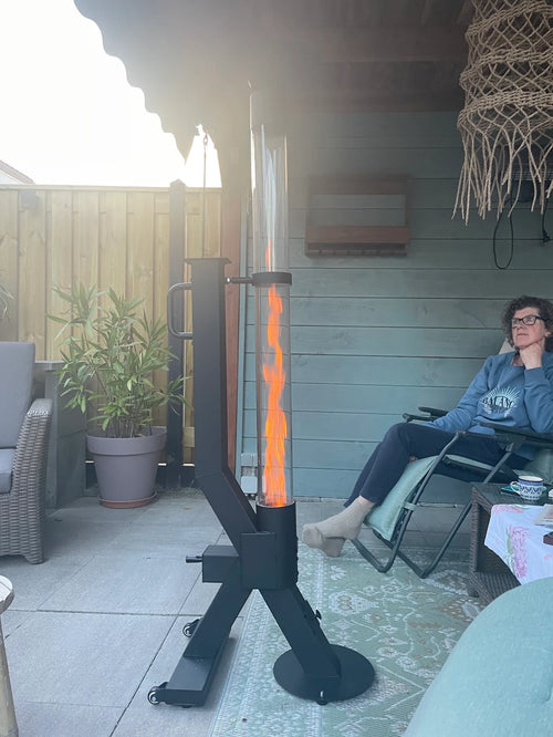 Jongen ontspant in een relaxstoel naast een brandende vuurzuil op pellets op een overdekt terras